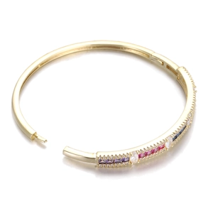 Close-up of gold hinged bangle featuring colorful rectangular gems and micro-pavé diamonds