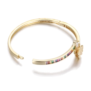 Close-up of golden bangle featuring colorful zircon stones and a crystal butterfly detail
