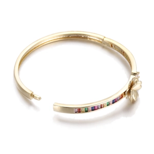 Detail of gold open bangle featuring colorful square zircons and a delicate floral accent