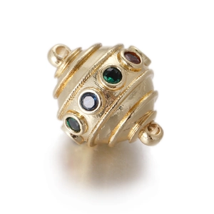 Macro detail of a golden spiral egg pendant with red, blue, and green gemstones