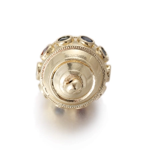 Macro shot of gold vintage bead charm with colorful gemstones and grain texture
