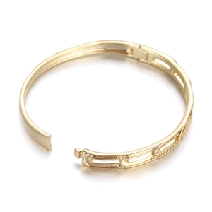 Close-up of golden geometric open bangle with pave cubic zirconia oval links