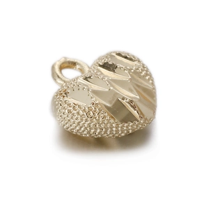 Macro shot of a vintage gold heart-shaped metal pendant with a textured M letter