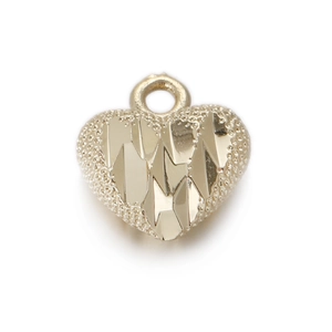 Detail view of heart-shaped gold-toned pendant featuring textured edges and faceted center