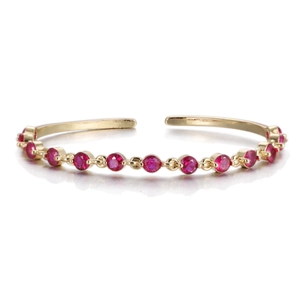 Detailed view of the gold open bangle set with brilliant red round-cut cubic zirconia