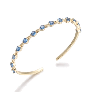 Macro view of gold plated open cuff bracelet with circular blue zircon gemstones