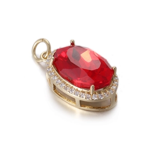 Detalle de colgante de gema roja ovalada con montura dorada y halo de circonitas