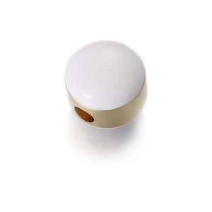 Macro shot of egg-shaped white enamel and gold metal jewelry bead with side hole