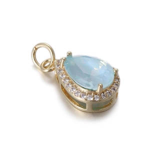 Detalle del colgante de gota de gema azul con metal dorado y halo de circonitas