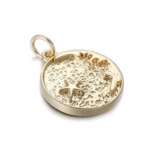 Macro detail of a gold plated round coin pendant with embossed starfish and ocean texture