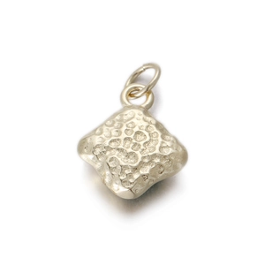 Detalle del colgante romboide dorado con textura martillada única y anilla para collar