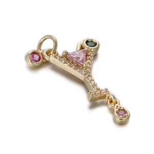 Detailed macro view of a gold pendant with pink and green gems on a clean white background