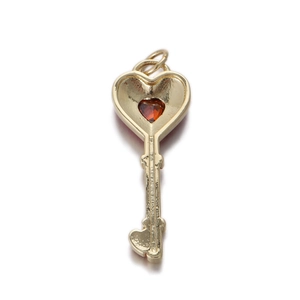 Detailed macro of a gold heart key pendant with a red gemstone and textured grip