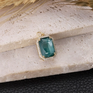 Colgante dorado con gema verde oscuro talla esmeralda y halo de circonitas brillantes