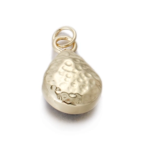 Macro detail of teardrop gold pendant featuring hammered texture and dual ring connectors