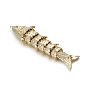Detailed macro of golden fish pendant with articulated joints and textured scales