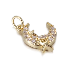 Macro shot of gold moon and star pendant with pink stones on white background