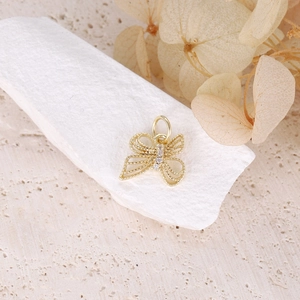 Bohemian gold butterfly charm with hollow wings and inlaid zircons on a white stone base
