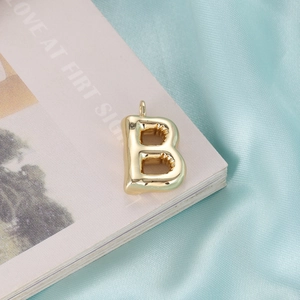 Fashionable golden bubble letter B pendant with glossy finish on silk background