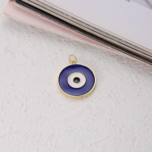 Macro shot of circular evil eye enamel pendant in gold frame with deep blue details