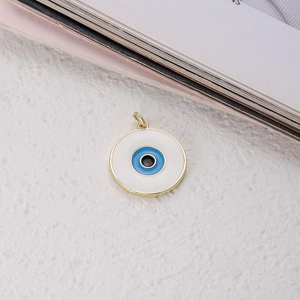 Detail of a copper evil eye charm with blue and white enamel inlay and golden finish