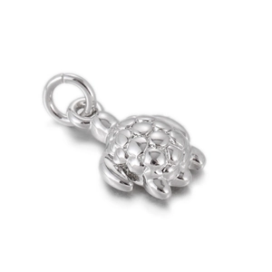 Macro detail of a polished sea turtle charm with embossed shell textures and a ring loop