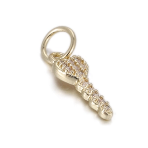 Close-up of golden key pendant featuring micro-paved rhinestones on a white background