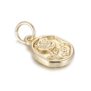 Vista macro detallada de un colgante ovalado de metal dorado con una rosa en relieve y grabado