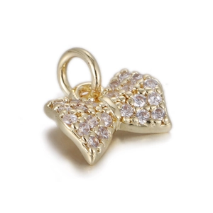 Macro detail of a golden bow pendant with clear zircon inlay for jewelry making