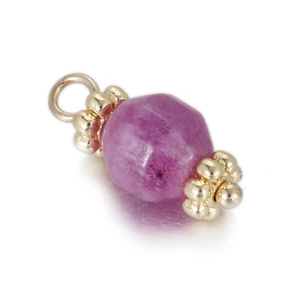 Macro shot of geometric faceted ruby red stone pendant with gold metal floral spacers