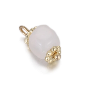 Detail of rose quartz pendant with ornate gold beaded caps on a reflective white surface