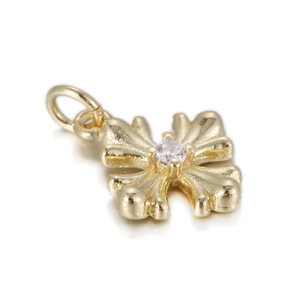 Macro shot of gold cross pendant with center zircon on a white reflective background