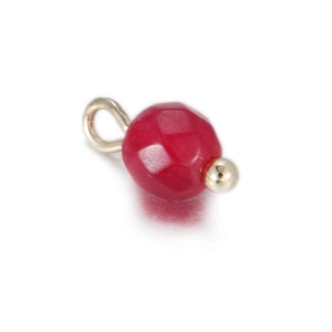 Macro shot of faceted dark red gemstone charm with gold metal loop for DIY jewelry