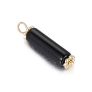 Macro view of a polished black stone cylinder pendant with golden floral metal end caps
