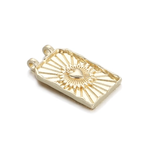 Detailed macro view of a gold tarot card pendant with embossed heart and sunburst texture