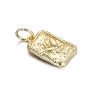 Macro view of gold-plated rectangular pendant with embossed butterfly and hammered texture
