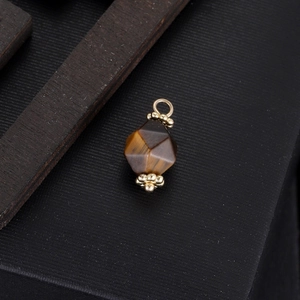 Tiger eye stone geometric pendant with gold metal caps on a dark textured background