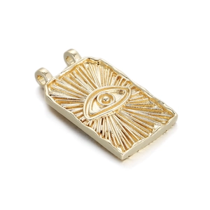 Close-up of golden rectangular evil eye charm with sunburst pattern and dual rings