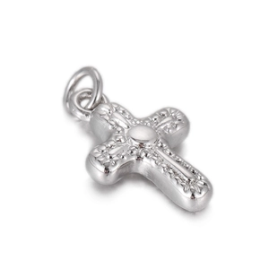 Detail of vintage silver cross pendant with embossed star patterns and polished jump ring
