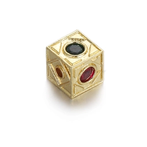 Macro detail of cube-shaped gold charm with colorful zircons and geometric carvings