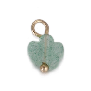 Macro-opname van een klavervormige groene stenen hanger met gouden oogje en fijne textuur