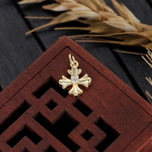 Golden cross pendant with zircon center on vintage wood and dried wheat background