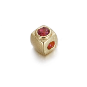 Macro view of a 14k gold-plated cube bead with a red zircon inlay and a center hole