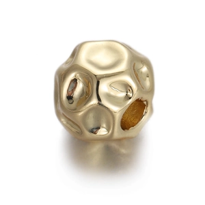 Detailed macro shot of a gold irregular textured metal bead with a central hole for DIY jewelry