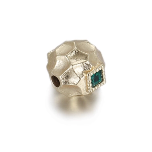 Detailed macro view of 14k gold copper bead with hammered texture and green zircon stone