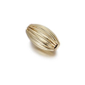 Macro detail of oval 14k gold plated spacer bead with vertical stripe texture and holes