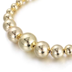Macro detail of polished gold beaded bracelet showing gradient mirror finish spheres