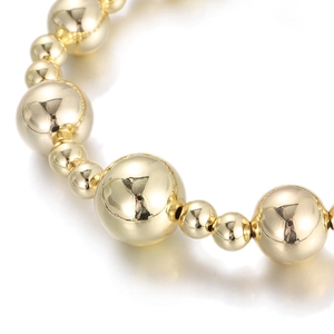 Macro shot of mirror-polished gold beads with metallic reflections on a copper bracelet