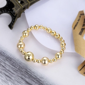 Detailed view of polished gold bead bracelet with mirror finish on a chic white background