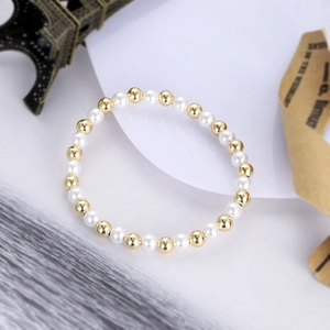Detail of gold copper beads and white imitation pearls on a stylish handmade bracelet